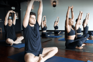 yoga class performing breathwork with arms raised